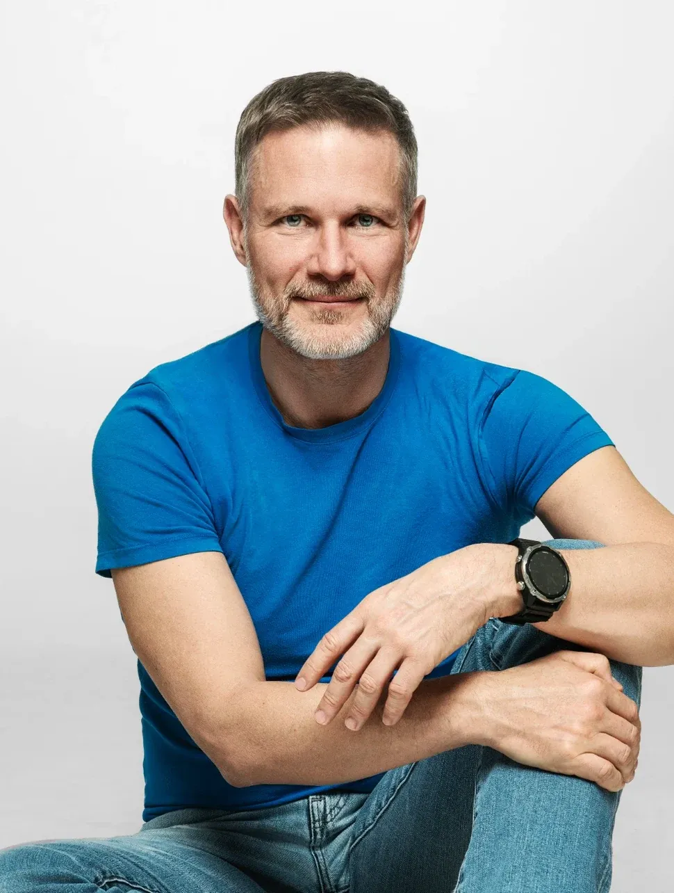 Piotr Urbanik – coach przywódców, portret w niebieskiej koszulce na szarym tle