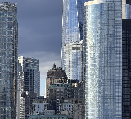 zdjęcie przedstawiające panorame miasta i kilka mniejszych starszych budynków na tle nowego wysokiego budownictwa szklanego